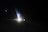 A dimly lit airplane wing with a logo is visible against the dark night sky. There is a bright light illuminating a section of the wing.
