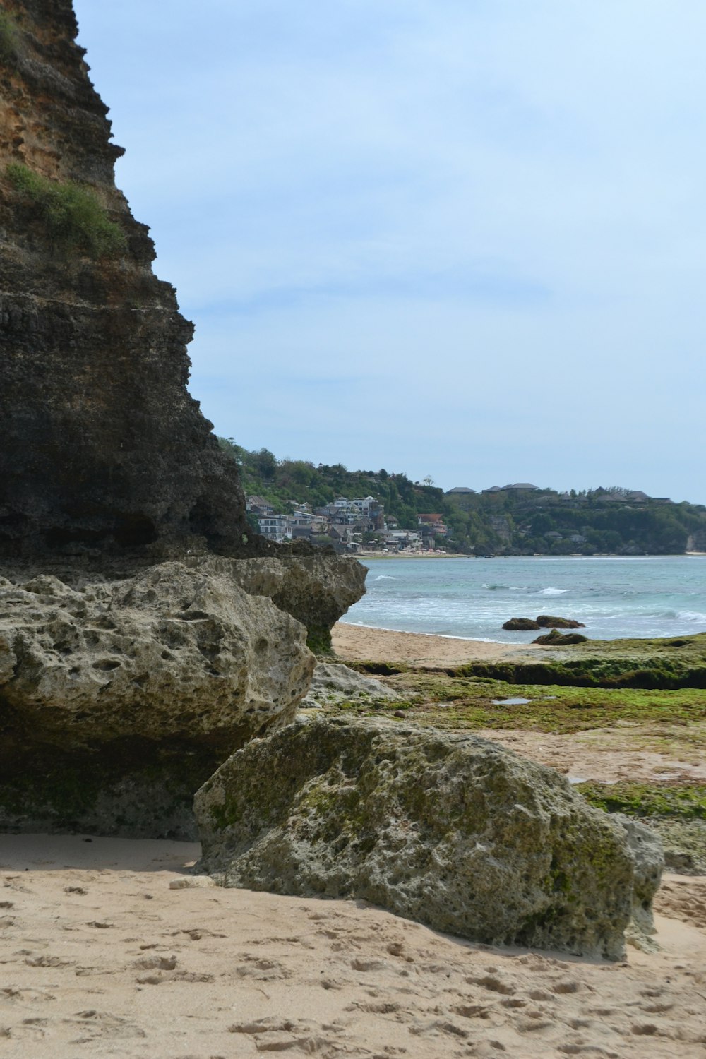 una grande roccia seduta in cima a una spiaggia sabbiosa