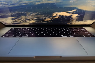 A laptop with its keyboard visible and the screen showing an image of a distant view of the Earth from space. The reflection of the keyboard is faintly visible on the screen.