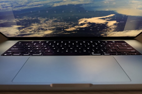 A laptop with its keyboard visible and the screen showing an image of a distant view of the Earth from space. The reflection of the keyboard is faintly visible on the screen.