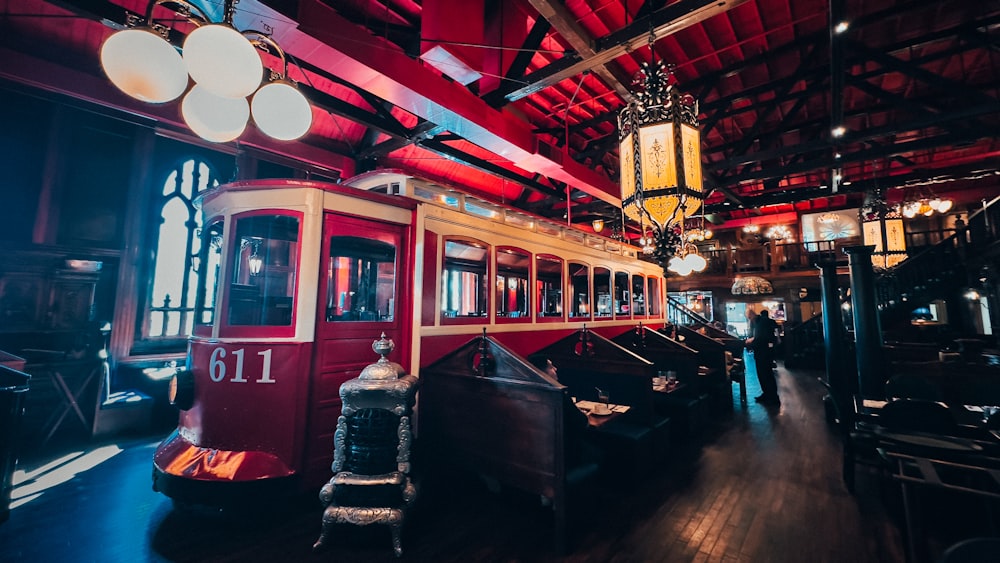 a red trolley car sitting inside of a train station