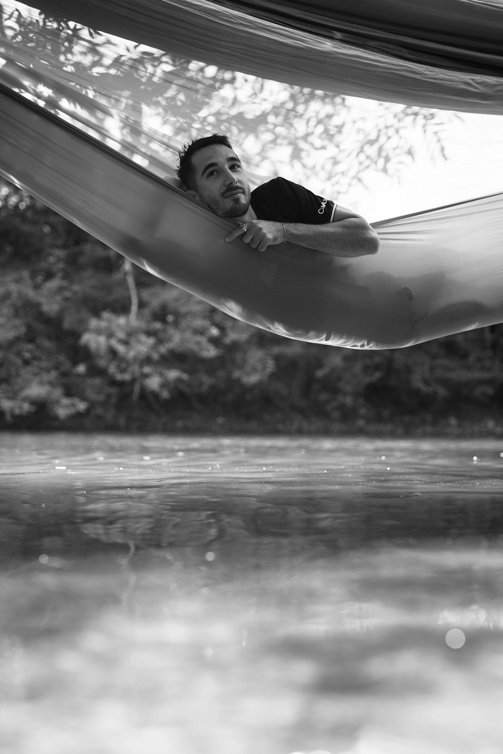 a man laying in a hammock on the water