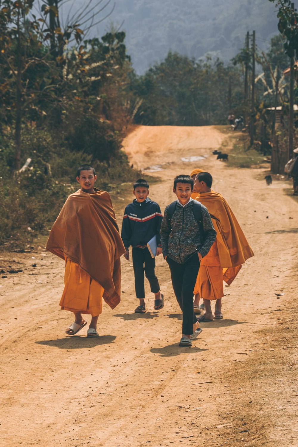 a group of people walking down a dirt road