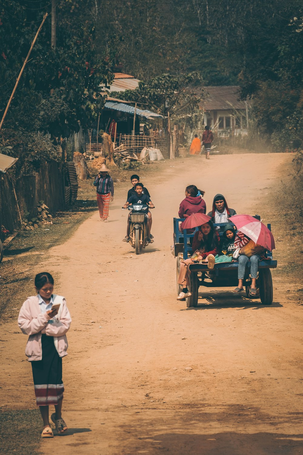 a group of people riding motorcycles down a dirt road