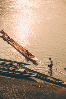 a man standing next to a boat on top of a body of water
