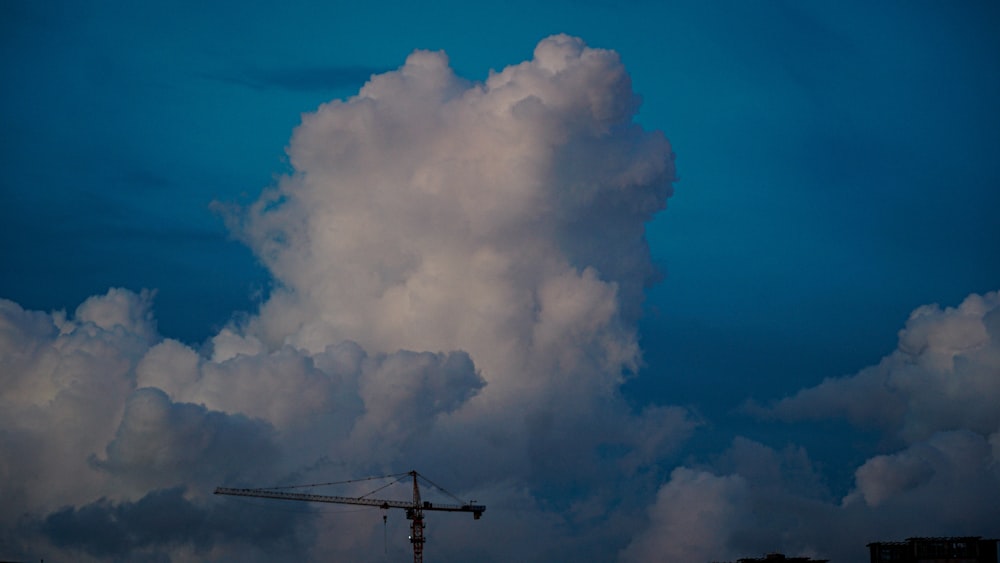 a large cloud looms over a building under a blue sky