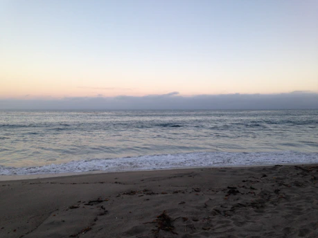 A serene beach at sunrise with gentle waves lapping the shore.