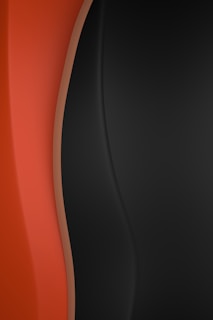 Smooth, flowing curves in shades of orange and black create an abstract, modern design with a contrasting tonal gradient.