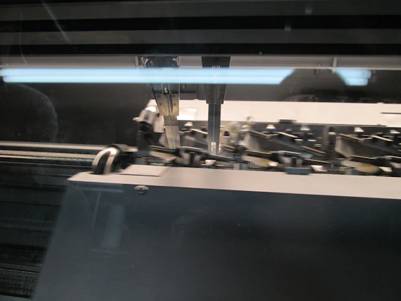 Close-up of a high-tech multi-head embroidery machine stitching a detailed pattern in a modern workshop.