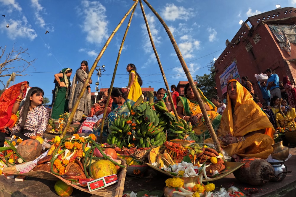 a group of people standing around a pile of fruit