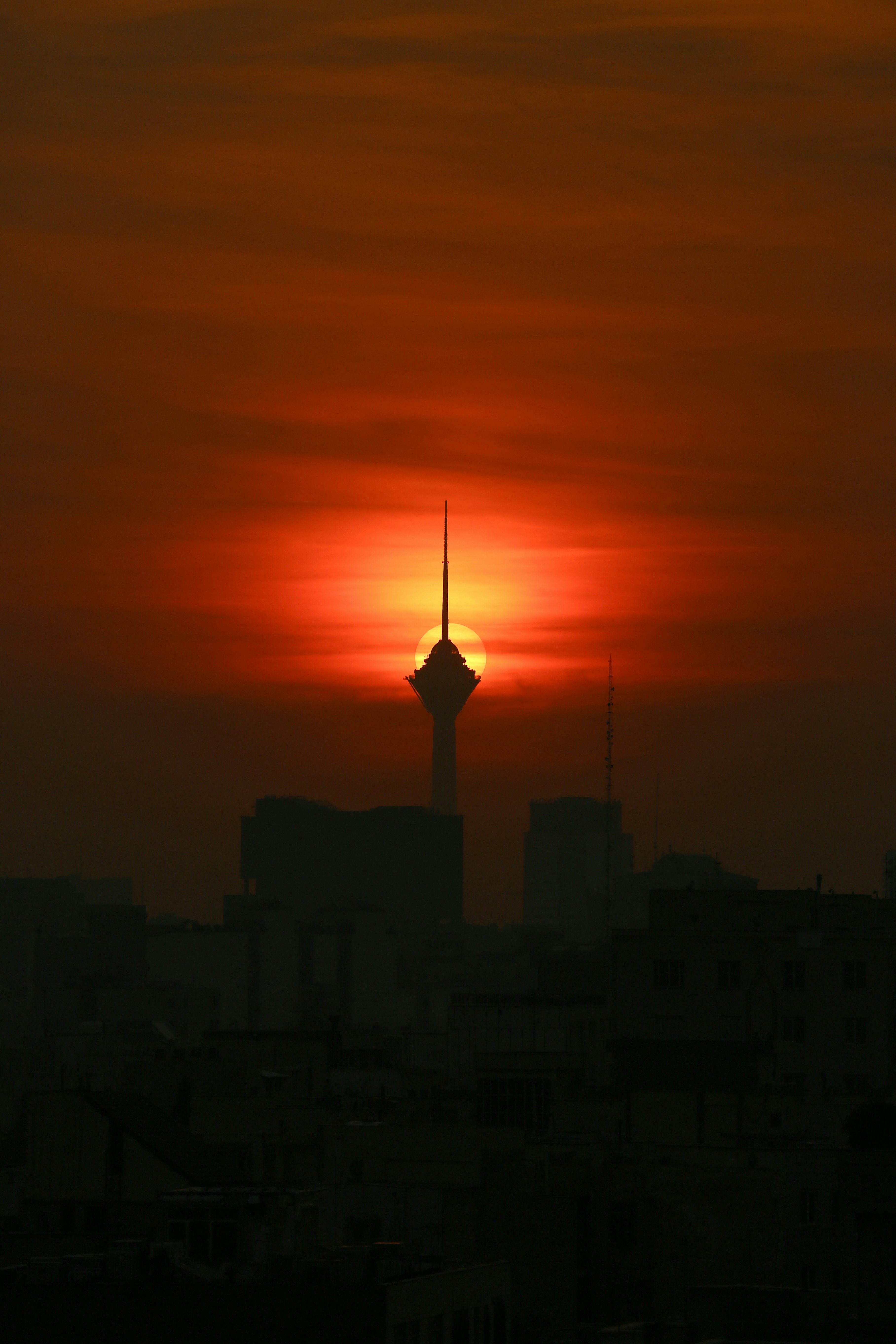 the sun is setting over a city with tall buildings