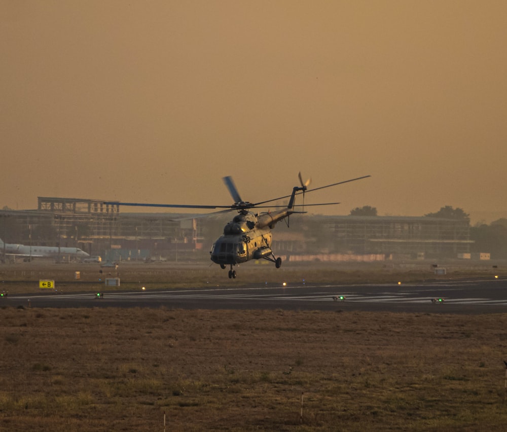 a military helicopter taking off from an airport runway
