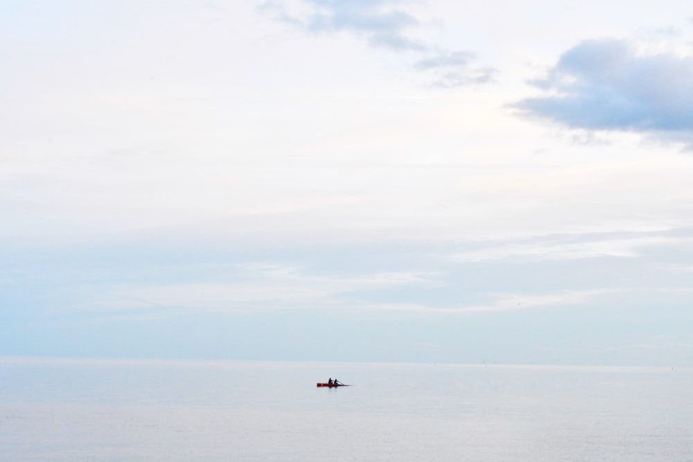 a lone boat floating in the middle of a large body of water