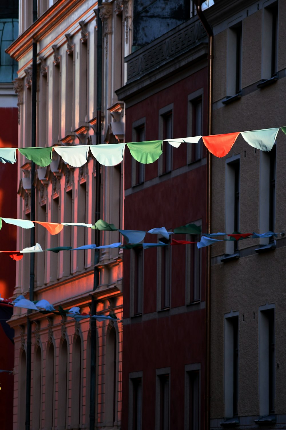 a group of flags flying in the air next to a building