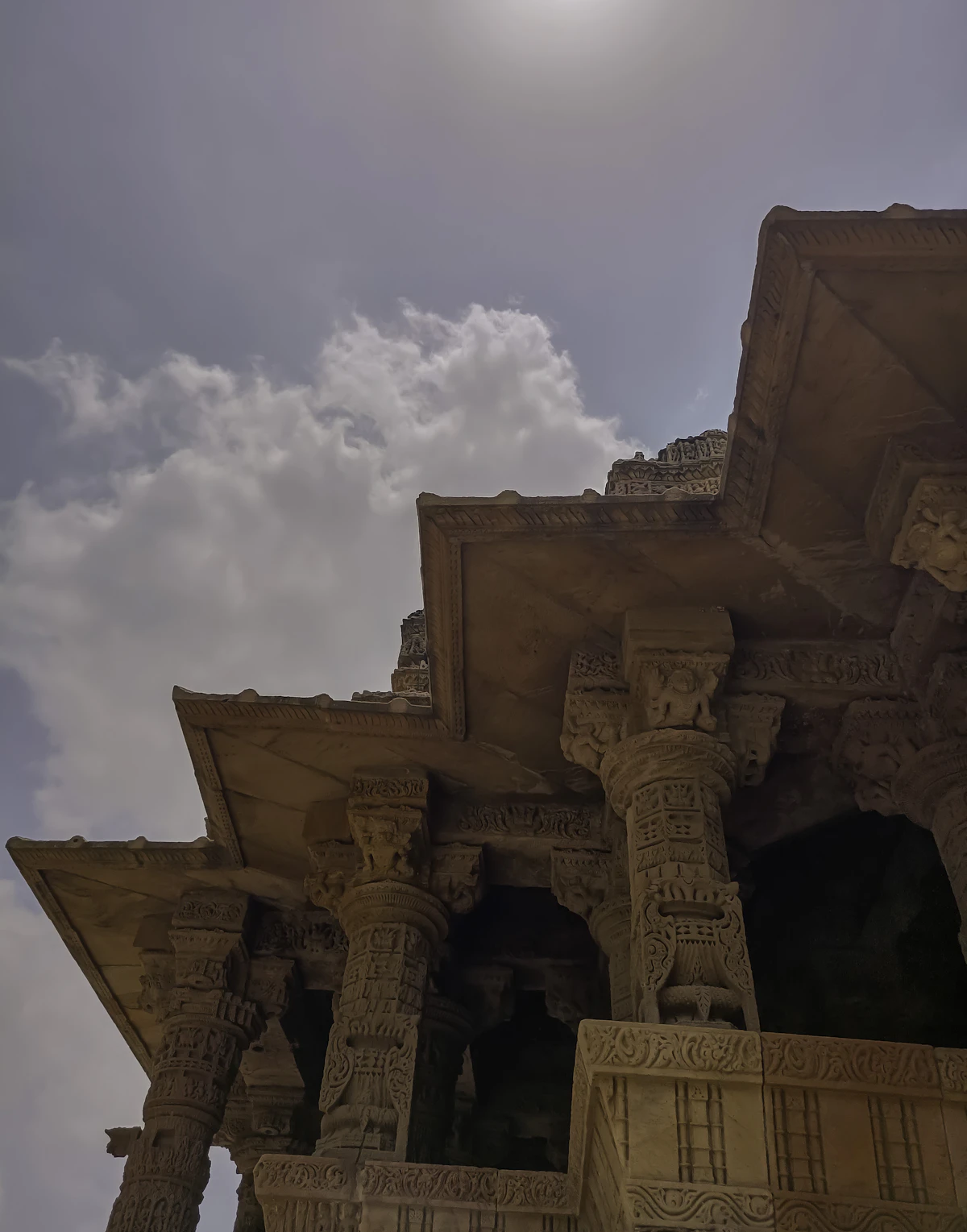 Sunlight breaking through clouds over an ancient structure, symbolic of Yoga carrying forward into the modern era