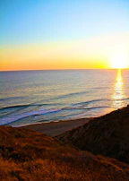 Scenic view of Cape Town’s rugged coastline meeting the deep blue ocean under a golden sunset.