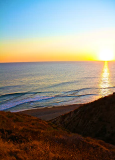 Scenic view of Cape Town’s rugged coastline meeting the deep blue ocean under a golden sunset.