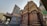 An intricately carved temple structure featuring vibrant statues and ornate designs, with solar panels visible in the background. The temple showcases a combination of colorful deities and traditional architectural elements.