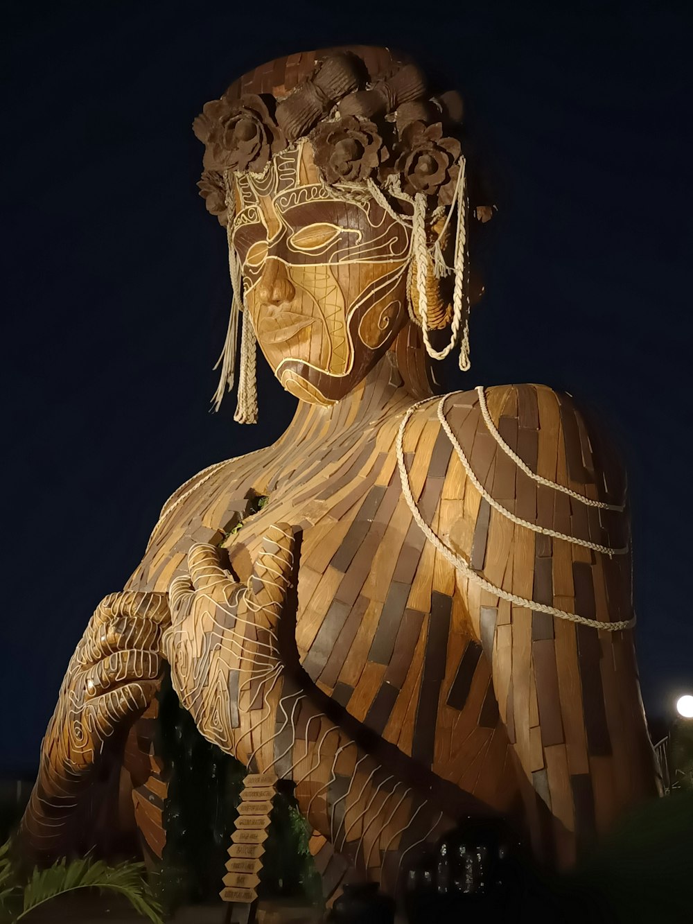 a large wooden statue of a woman with flowers on her head