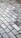 A detailed pattern of rectangular marble tiles with varying shades of gray and white, bordered by thin dark brown grout lines. The tiles are laid out in an offset arrangement, creating a visually interesting grid.