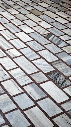 Precision-cut marble tiles arranged in a grid pattern on a charcoal background.