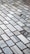 A detailed pattern of rectangular marble tiles with varying shades of gray and white, bordered by thin dark brown grout lines. The tiles are laid out in an offset arrangement, creating a visually interesting grid.