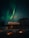 A cozy cabin under a vibrant aurora borealis sky in the Arctic wilderness.