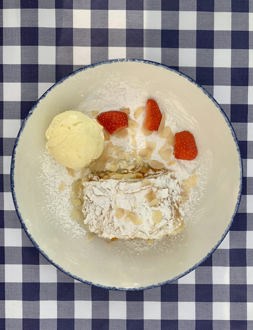 une assiette blanche surmontée d’un dessert et d’une boule de glace