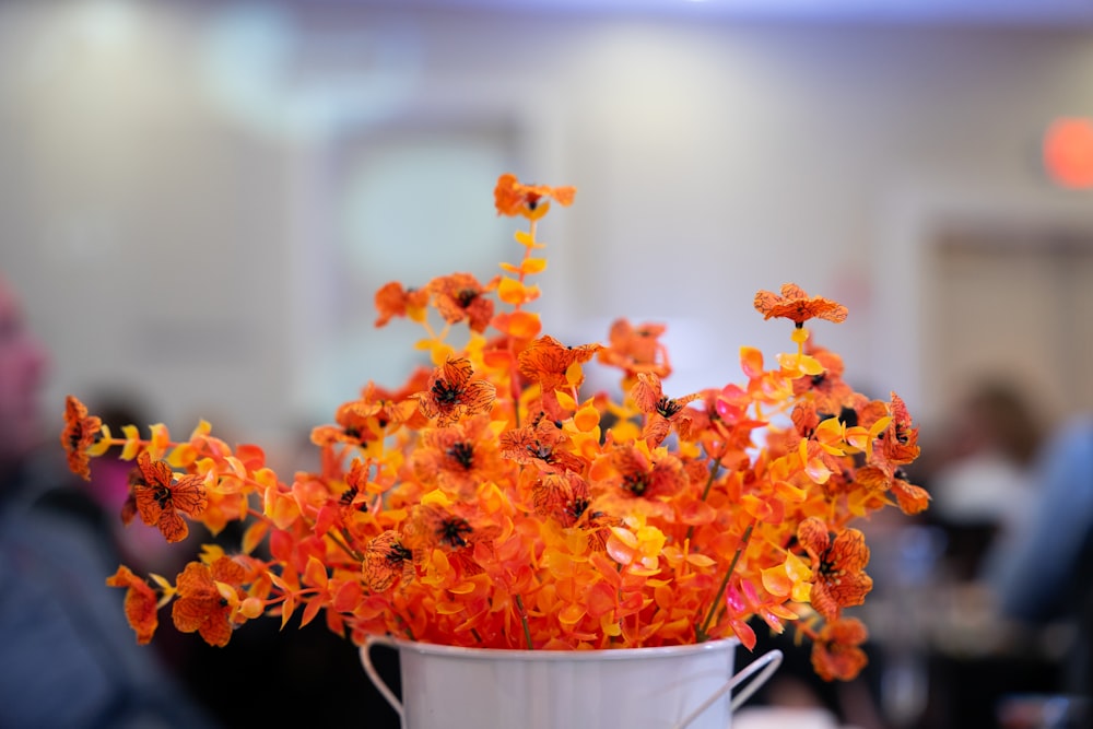 a white vase filled with orange flowers on top of a table