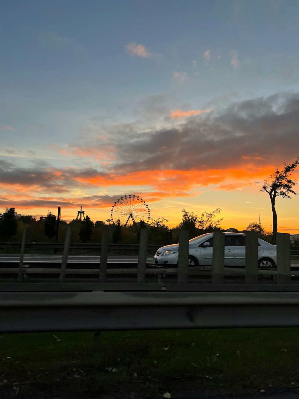 a white car driving down a highway next to a ferris wheel