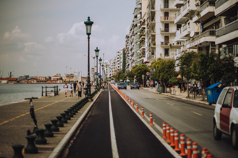 a street lined with orange traffic cones next to a body of water