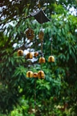 Decorative garden wind chime gently swaying in a soft breeze against a blue sky.