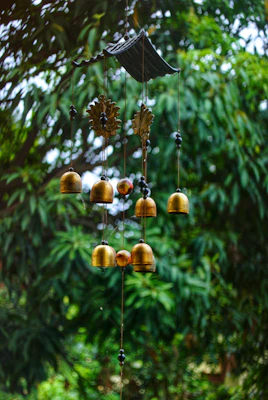 Charming outdoor decor including lanterns and wind chimes hanging from a leafy tree branch.