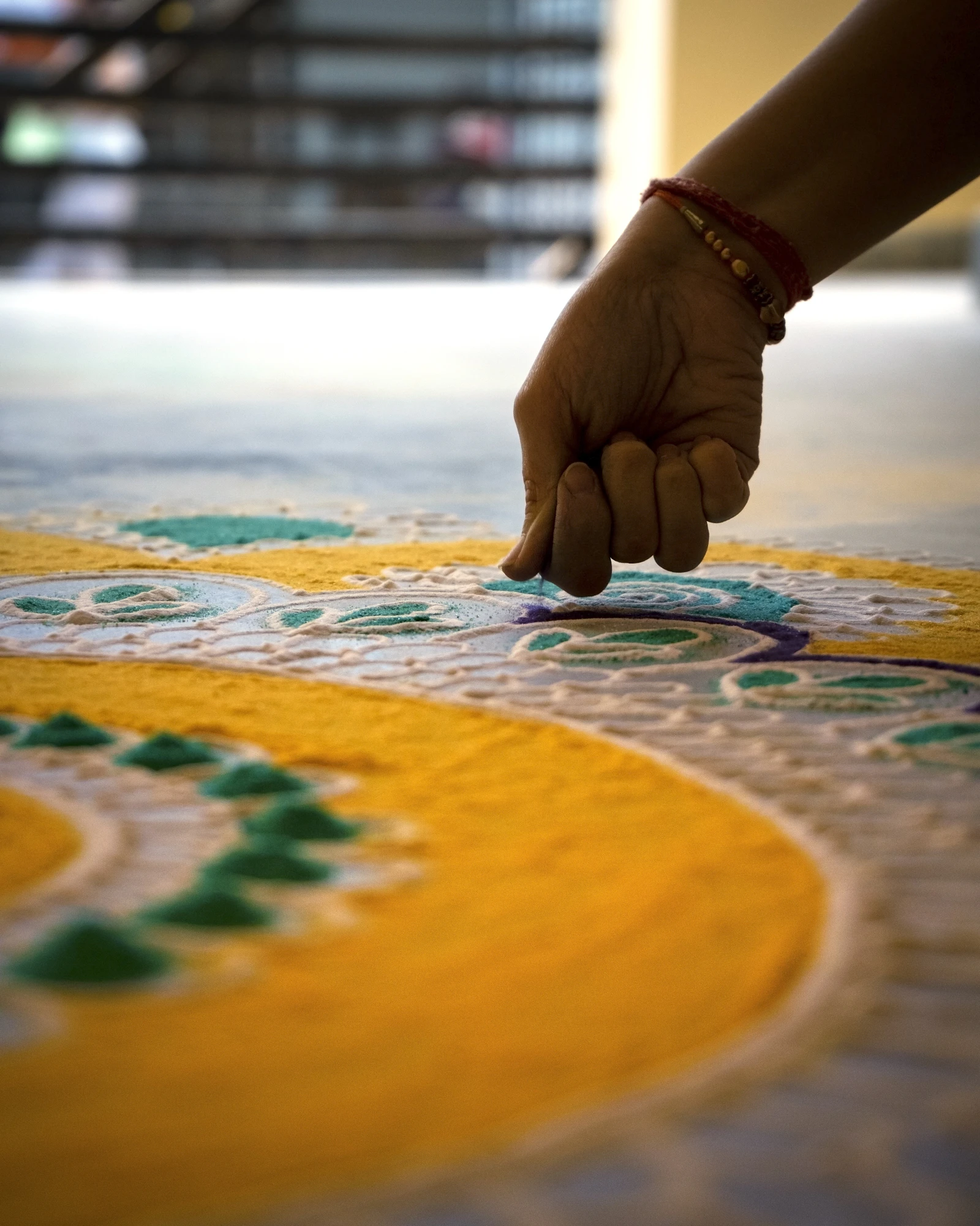 Hands creating a colourful rangoli design