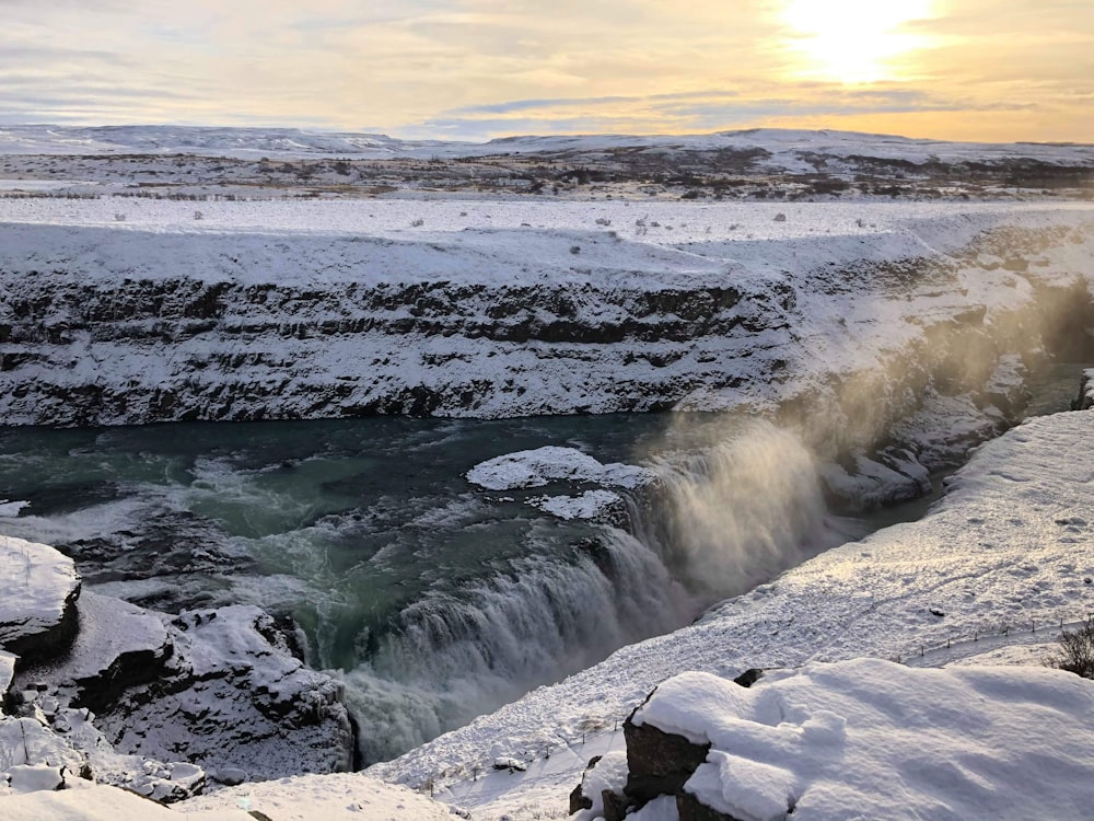 the sun is setting over a frozen waterfall