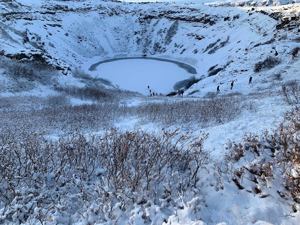 a snow covered field with a lake in the middle of it