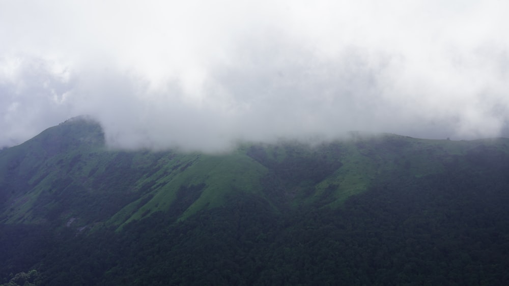 a mountain covered in green grass and clouds