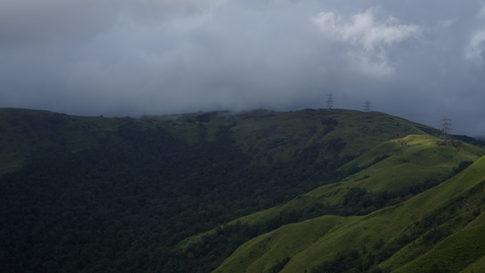 a hill covered in lush green grass under a cloudy sky