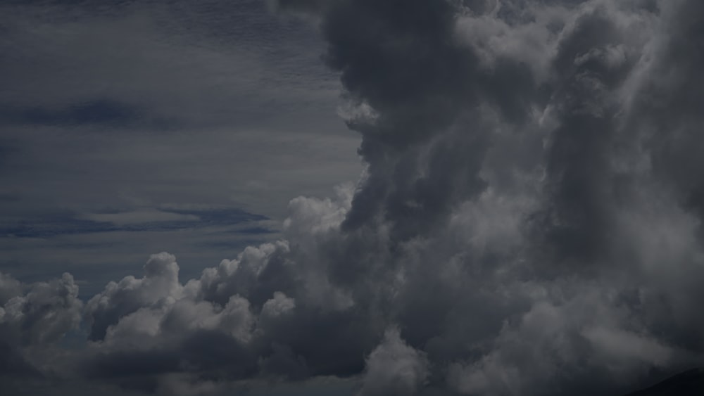 a plane flying through a cloudy sky with a mountain in the background