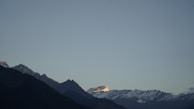 A panoramic view of a mountain range at sunrise, with golden light flooding the peaks.