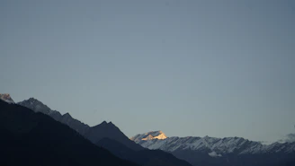 A panoramic view of rugged mountain peaks bathed in golden sunlight at dawn
