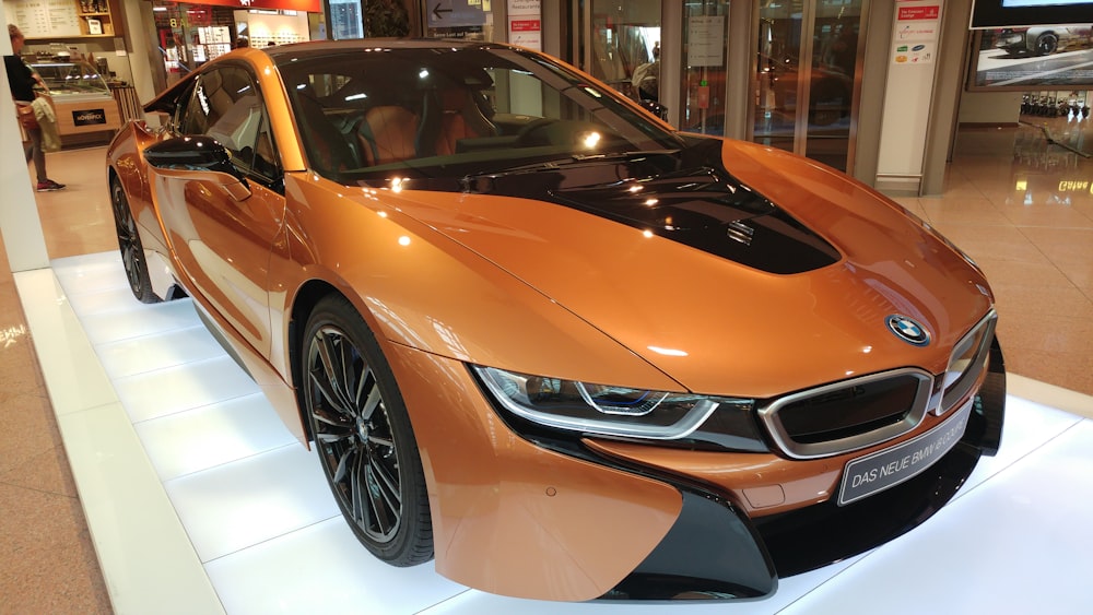 Une voiture de sport orange est exposée dans une salle d’exposition