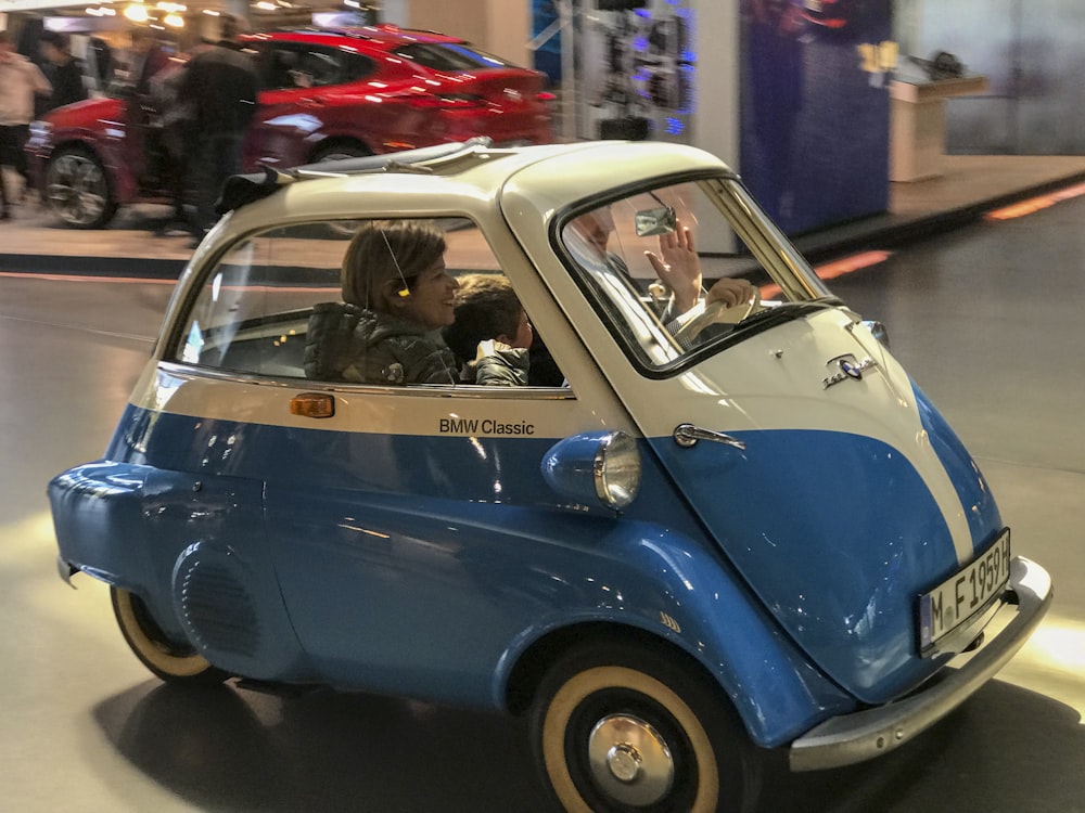 Une petite voiture bleue et blanche roulant dans une rue