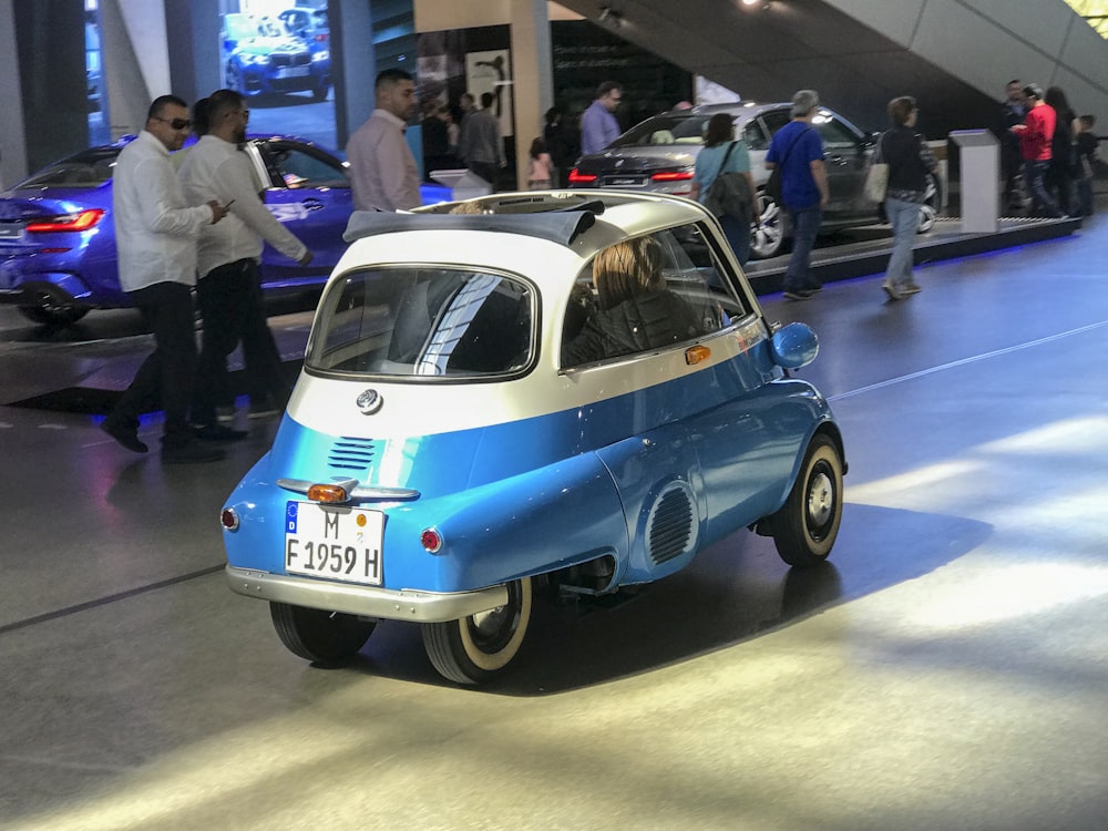 um pequeno carro azul e branco em exibição em um salão de carros