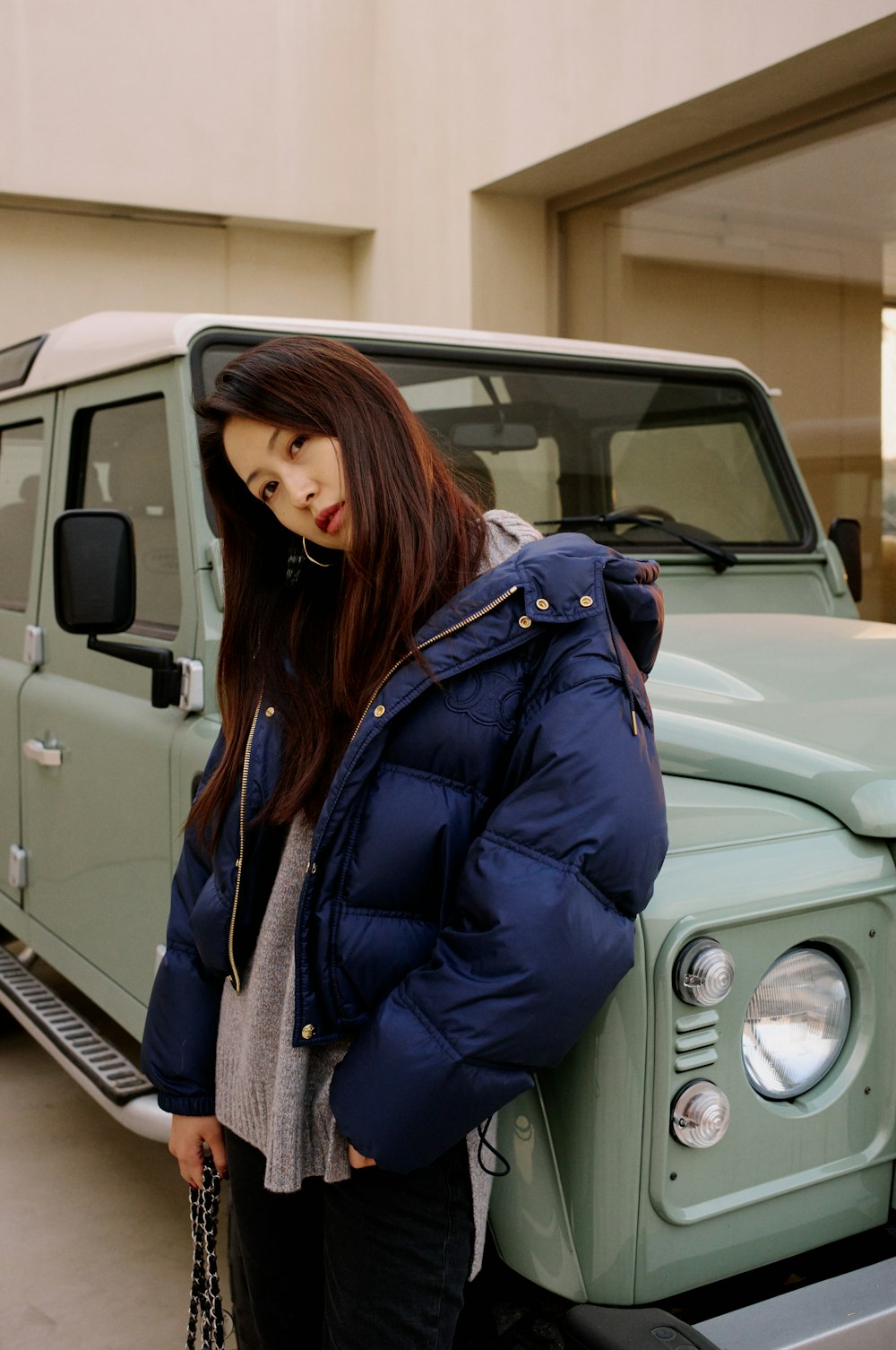 a woman standing next to a green jeep