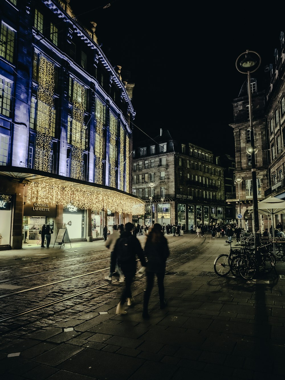 a couple of people walking down a street at night