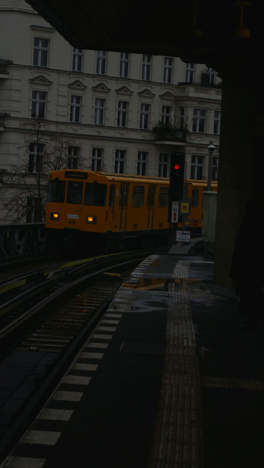 a yellow train traveling down train tracks next to a tall building