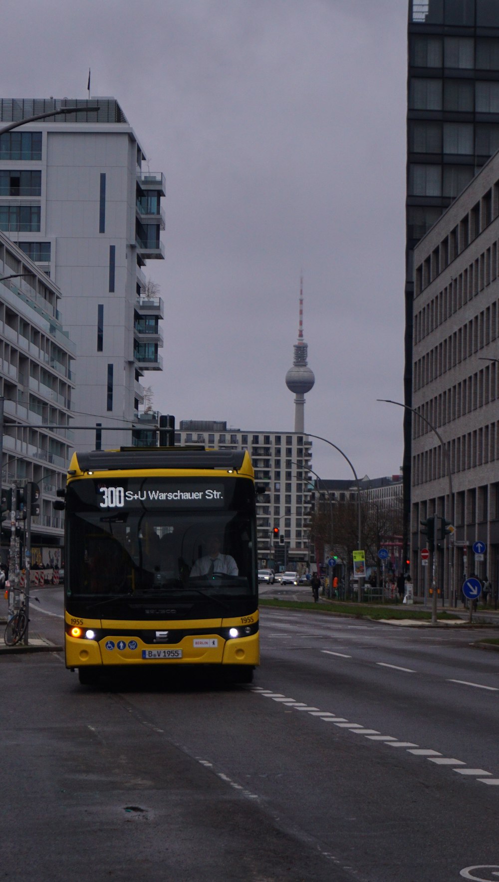 a yellow bus driving down a street next to tall buildings