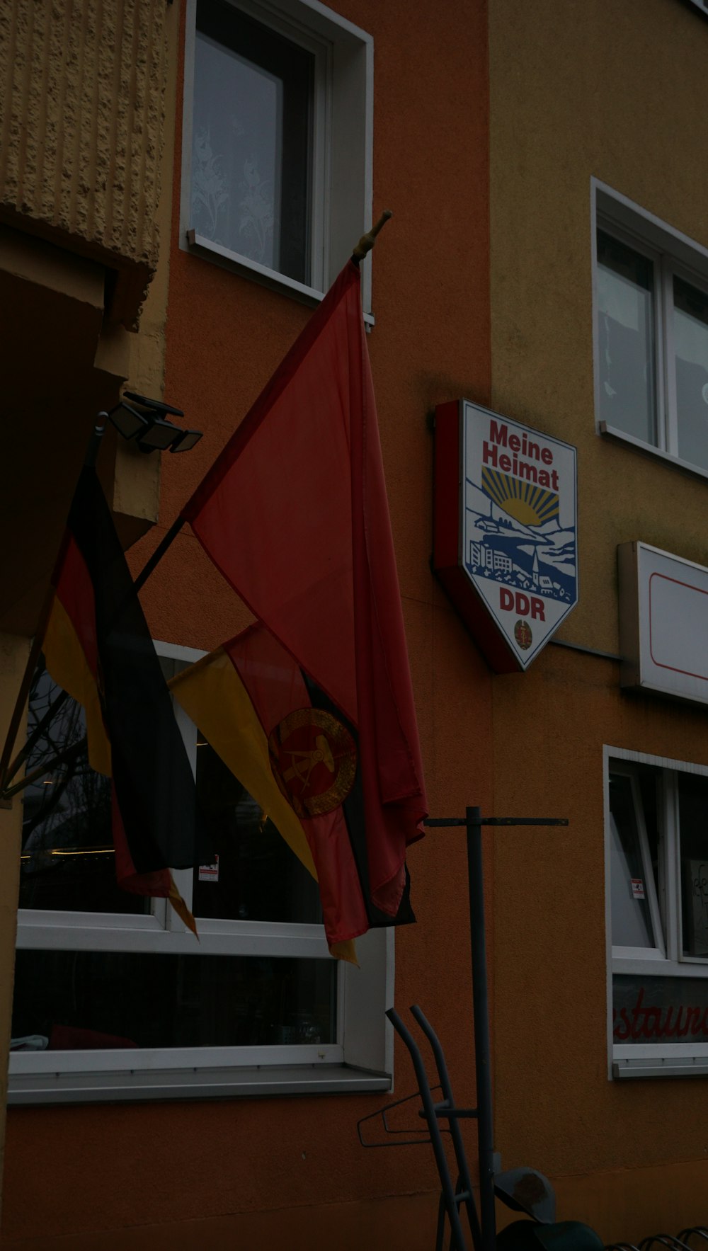 a red, yellow and black flag hanging outside of a building