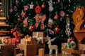 A festive Christmas scene featuring a beautifully decorated tree with red and white ornaments, ribbons, and lights. Beneath the tree are various wrapped gifts and a wooden figure of a reindeer. A decorative Santa ornament hangs on the tree, adding to the holiday atmosphere. A wooden reindeer sculpture and other handcrafted decorations are also present.